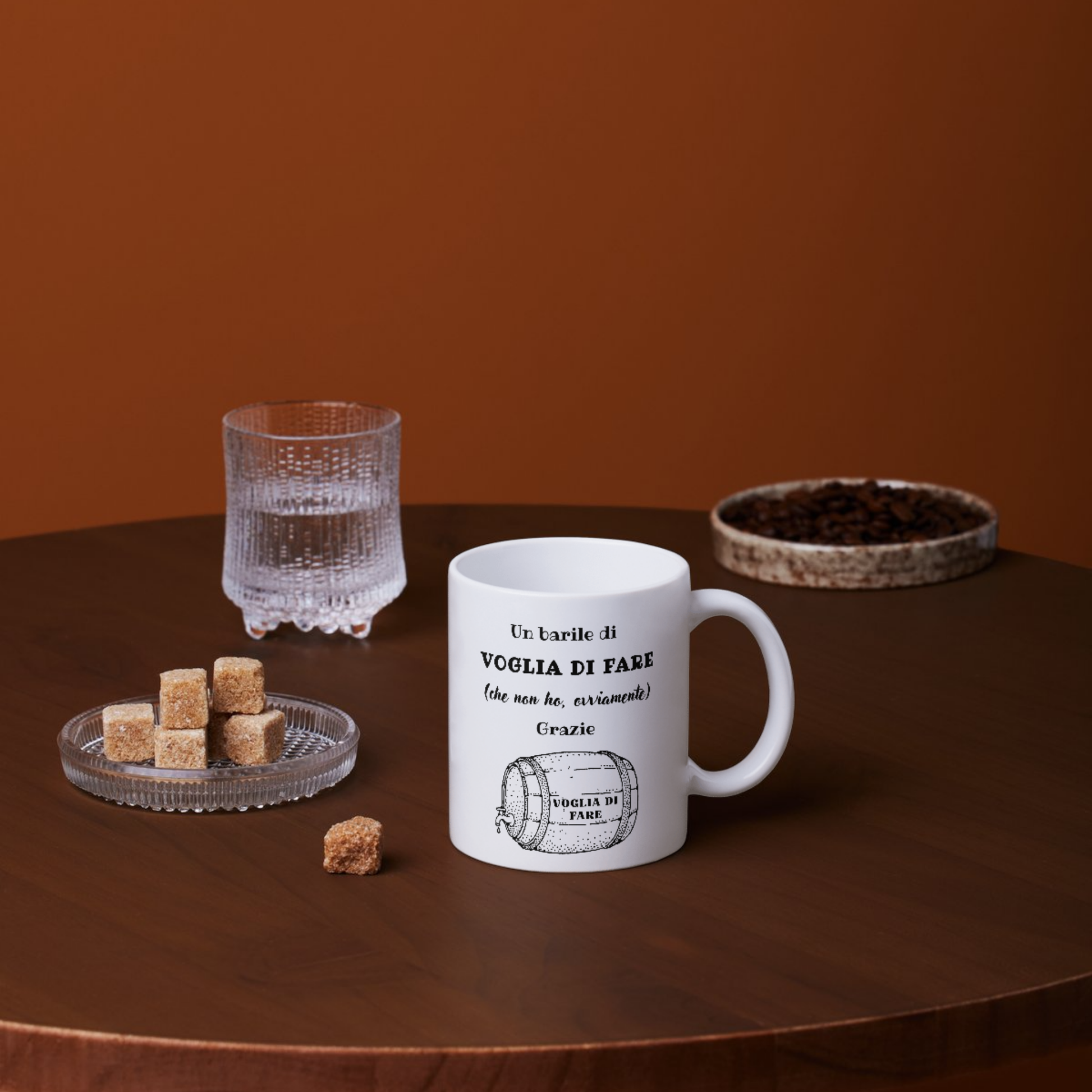 Tazza bianca con scritta "Un barile di VOGLIA DI FARE (che non ho, ovviamente), Grazie" (fronte), su tavolino